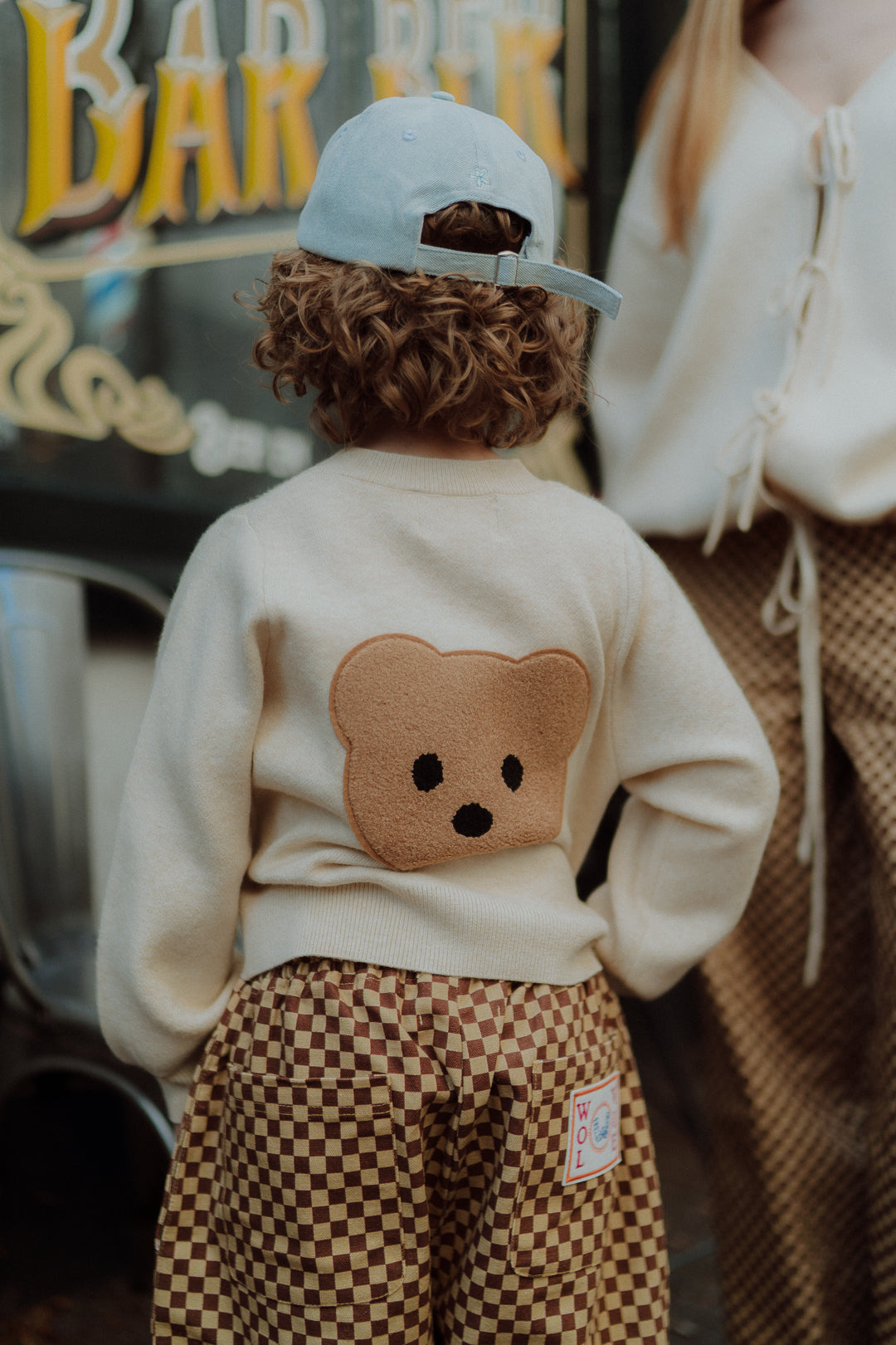 Kind wearing cream teddy bear sweater and brown checkered pants by Wolvie