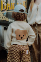 Kind wearing cream teddy bear sweater and brown checkered pants by Wolvie