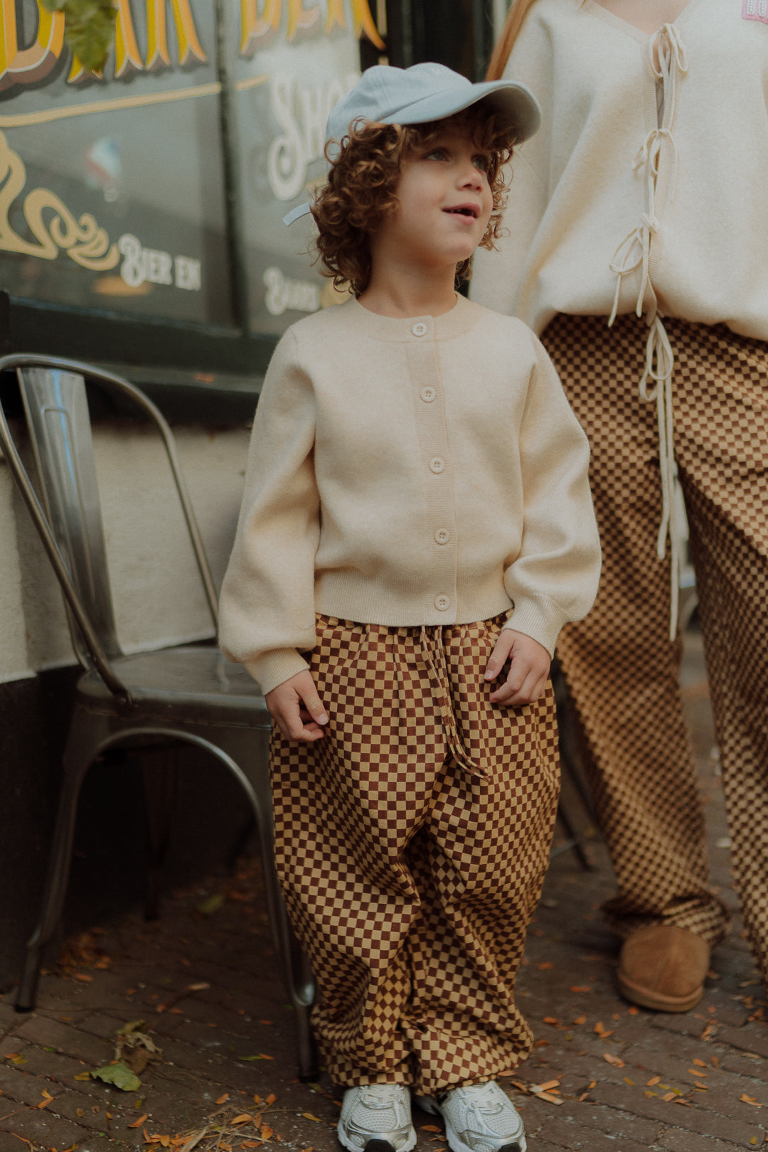 Matching kids outfit with neutral cardigan and checkered pants by Wolvie Women & Kids.  