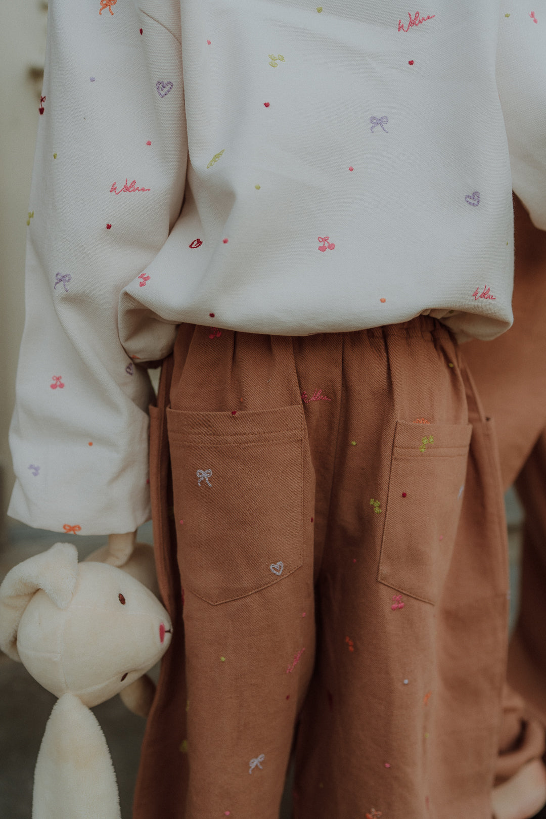 Kids wearing camel embroidery pants with colorful embroidered details from Wolvie SS26 collection