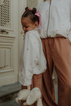 Mom and child wearing matching camel pants and embroidered blouse from Wolvie SS26 collection.