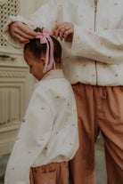 Close-up of mom and daughter wearing matching embroidered outfit with bow detail from Wolvie SS26 collection.