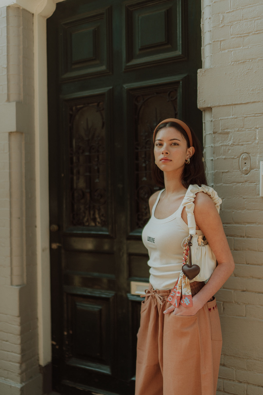 Woman wearing a neutral WOLVIE summer outfit with a white ruffle top and relaxed brown pants
