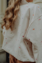 Close-up of a cream oversized sweater with colorful embroidered details for women