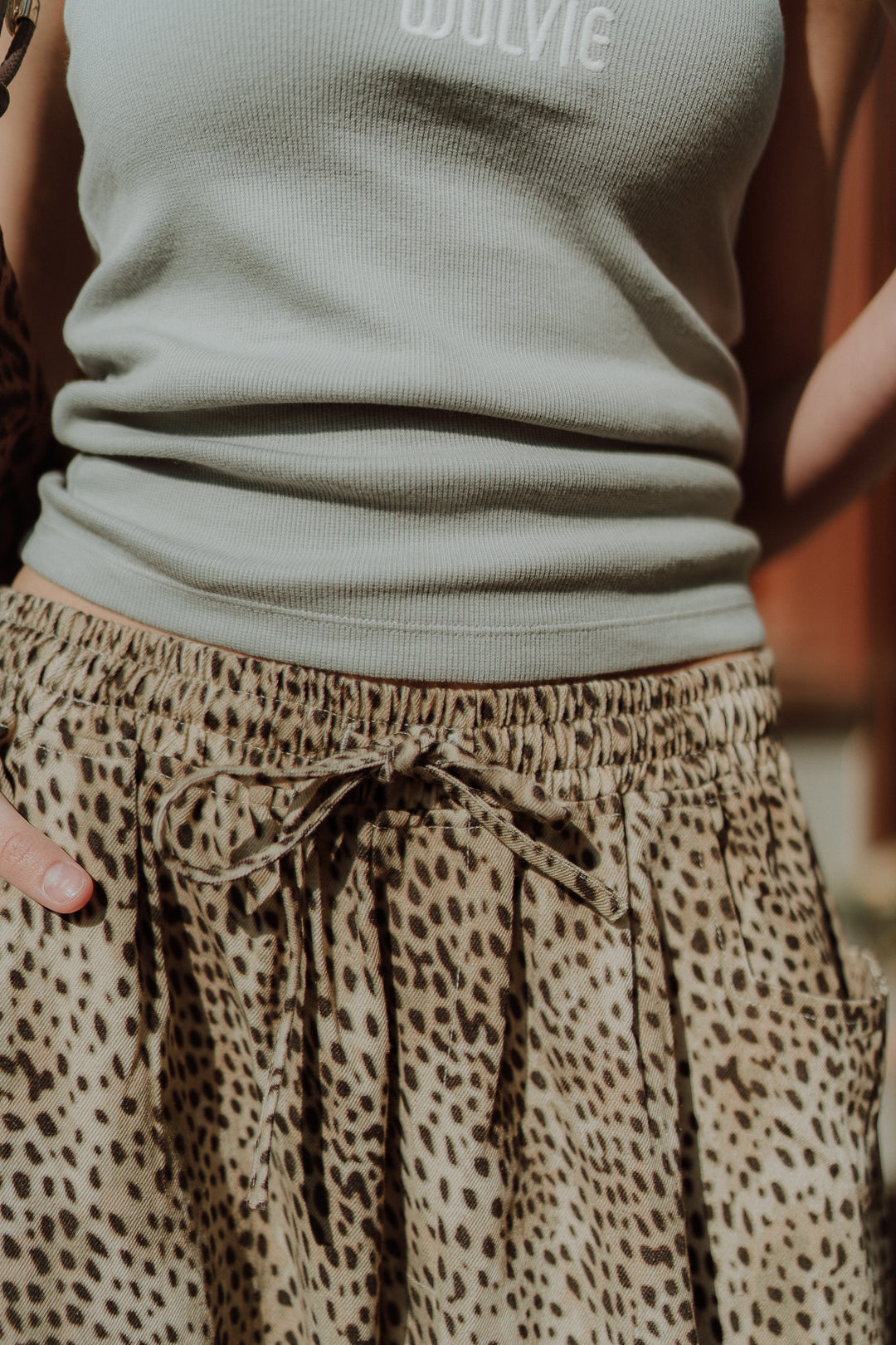 Close-up of women’s leopard print pants with neutral ribbed top in casual summer outfit