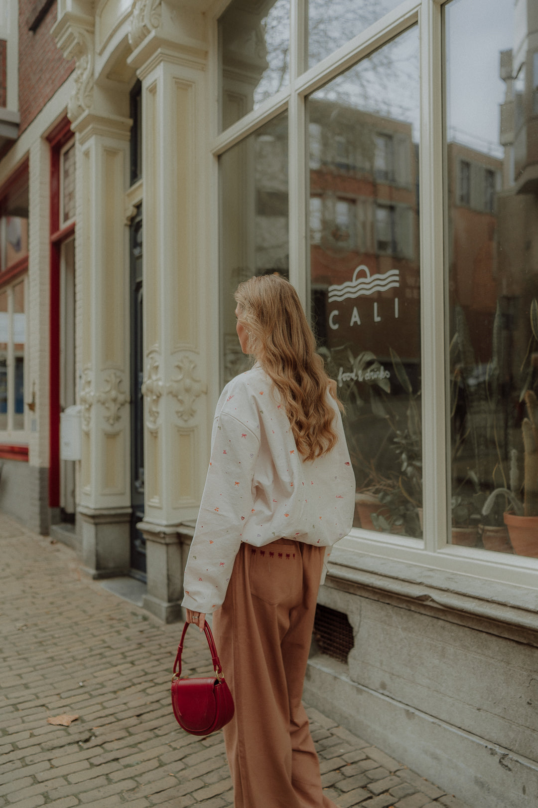 Woman wearing a matching outfit with embroidered sweater and brown pants walking through the city