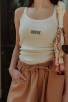 Woman wearing a white ribbed top with wide leg pants and shoulder bag