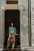 Woman wearing leopard print pants and a striped top standing in front of a door in a summer outfit by Wolvie