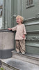 Curly-haired child wearing leopard print pants and a striped oversized shirt in a trendy boys outfit outdoors