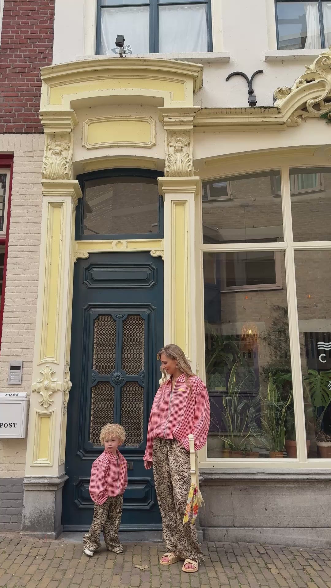 Mother and child wearing matching WOLVIE sweaters and leopard print pants in front of store.