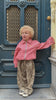  Child wearing leopard print pants and a red gingham jacket in a trendy kids outfit standing outdoors