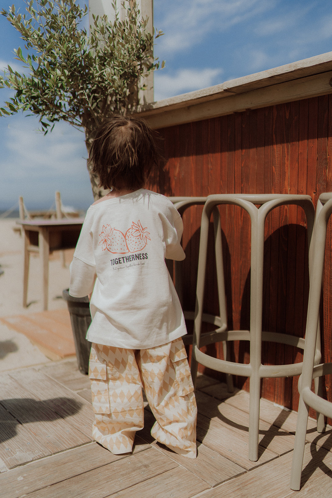 Child wearing a Togetherness graphic t-shirt and printed pants 